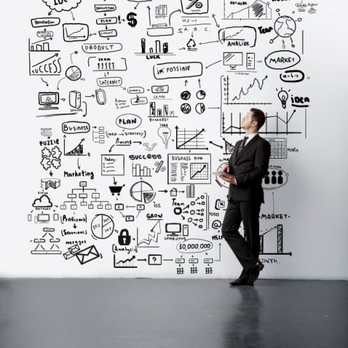 young man lookig at drawing business concept on wall